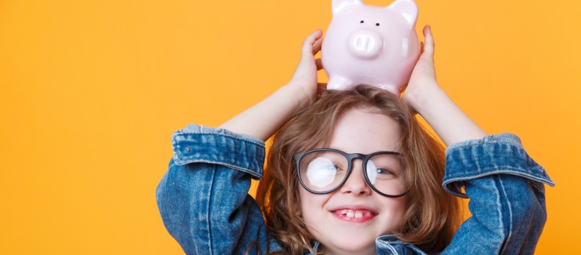 Little girl holding a piggy bank on her head